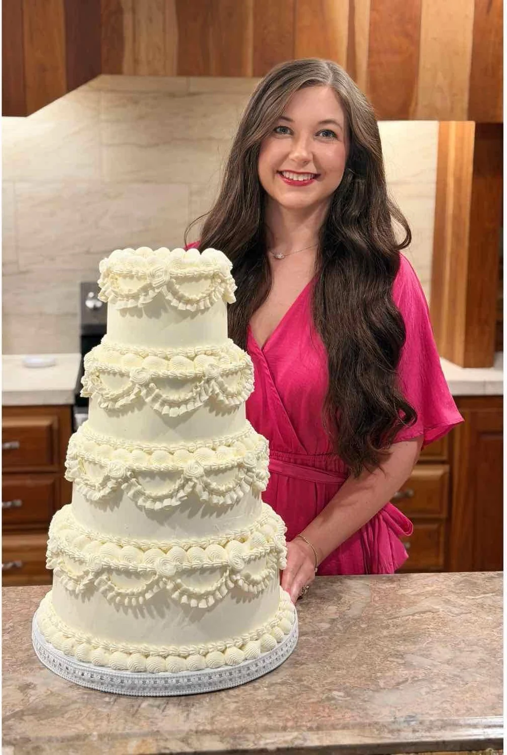 Dana, the baker behind Sugar Blossom Cakes, beside a decorated tiered cake